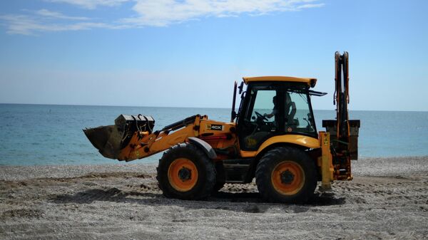 Трактор ровняет щебень на пляже в Ялте