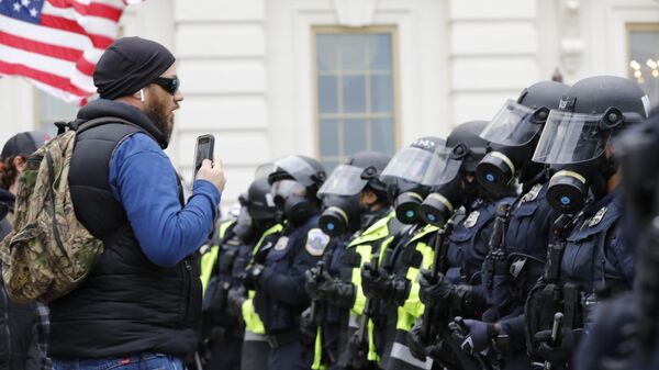 Сотрудники полиции и участник акции протеста сторонников действующего президента США Дональда Трампа у здания конгресса в Вашингтоне