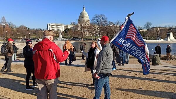 Мужчина с флагом сторонников Дональда Трампа на Капитолийском холме в Вашингтоне