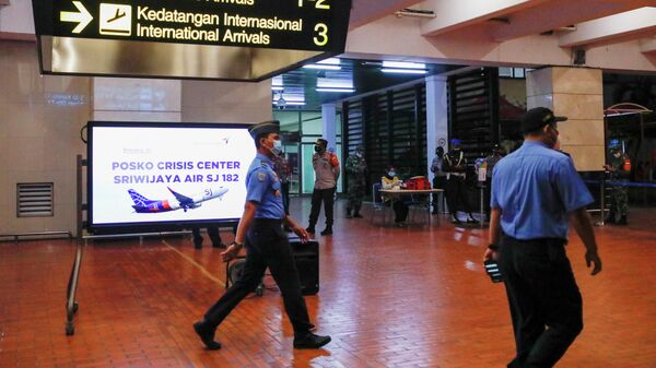 Сотрудники рядом с кризисным центром, организованным в аэропорту Джакарты, после крушения самолета компании Sriwijaya Air