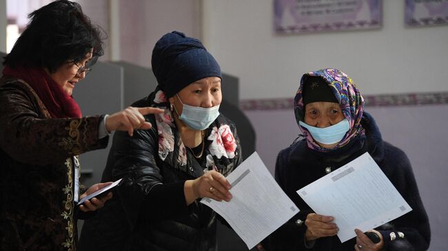 Женщины с бюллетенями на одном из избирательных участков в Бишкеке во время голосования на досрочных выборах президента Кыргызской Республики
