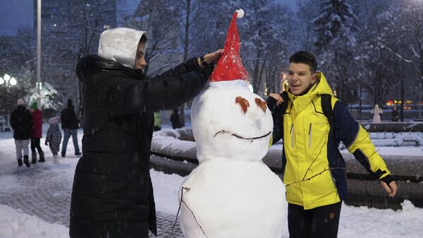 Молодые люди лепят снеговика в сквере им. Жукова в Краснодаре