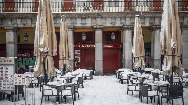 Занесенные снегом во время снегопада столки в летнем кафе на Главной площади в Мадриде