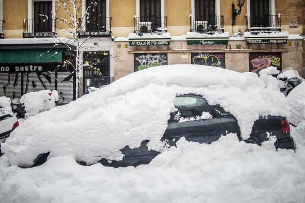 Занесенный снегом автомобиль на одной из улиц в Мадриде