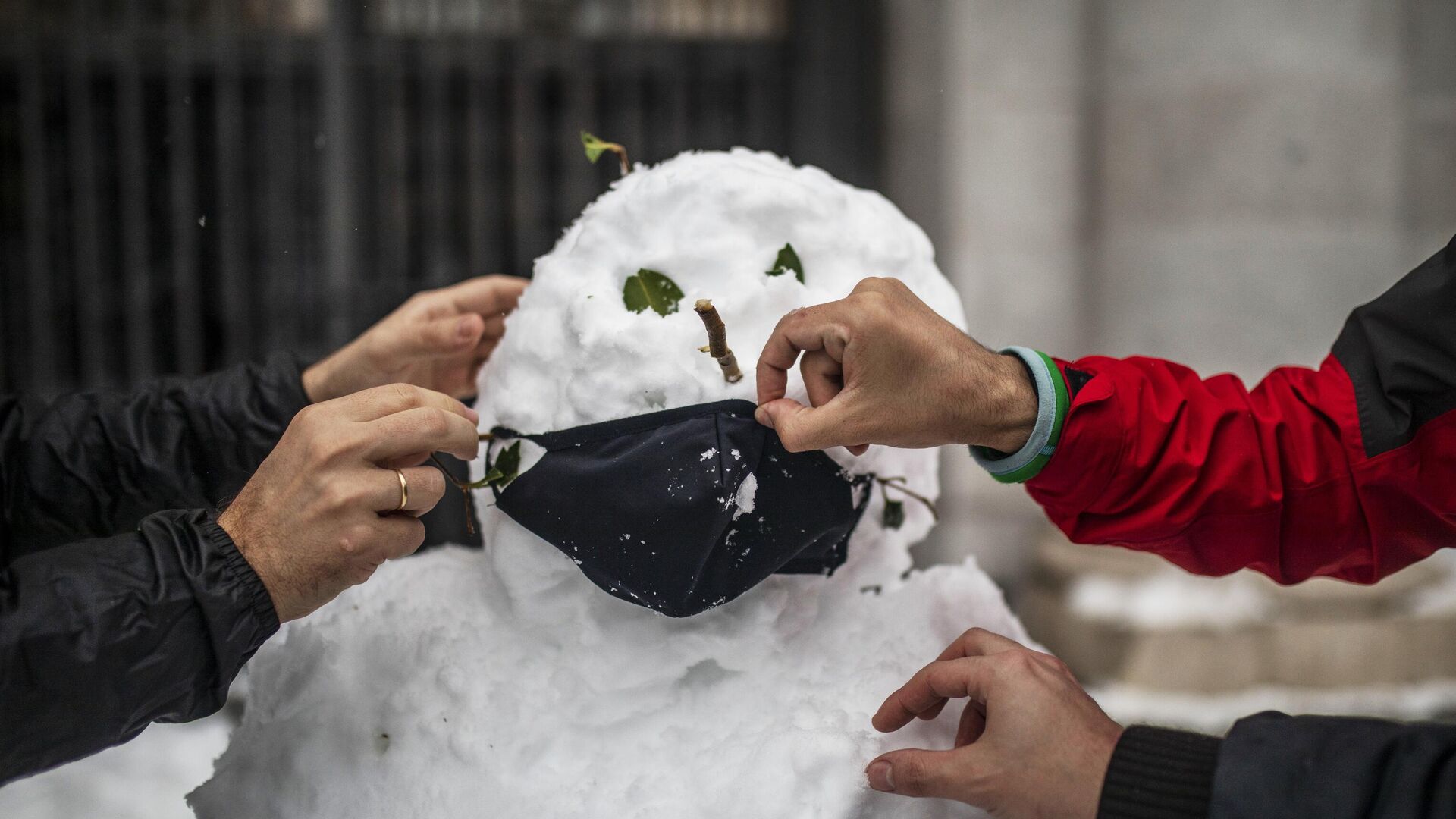 Люди надевают маску на слепленного снеговика на одной из улиц в Мадриде - РИА Новости, 1920, 02.02.2021