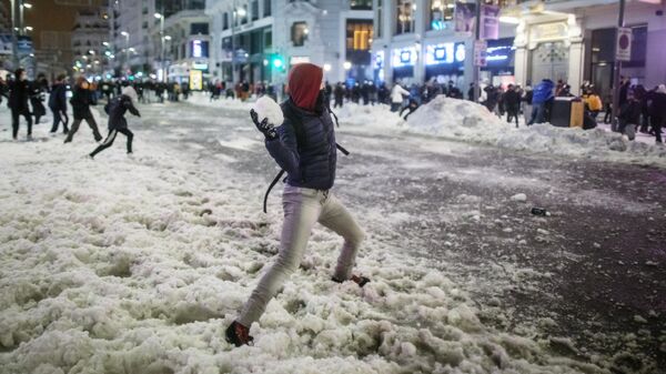 Юноша бросает снежок во время игры в снежки на площади Кальяо в Мадриде