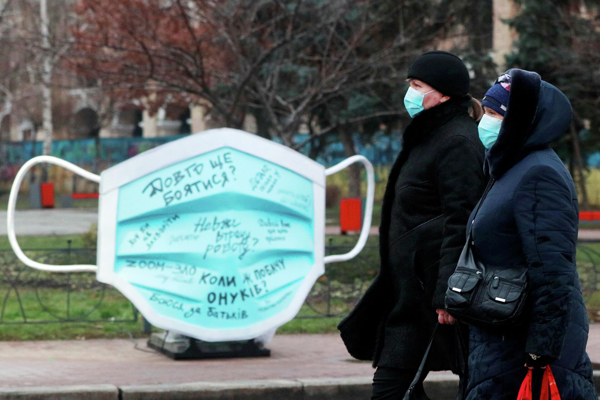 Женщины проходят мимо инсталляции в виде защитной маски на улице в Киеве - РИА Новости, 1920, 16.01.2021
