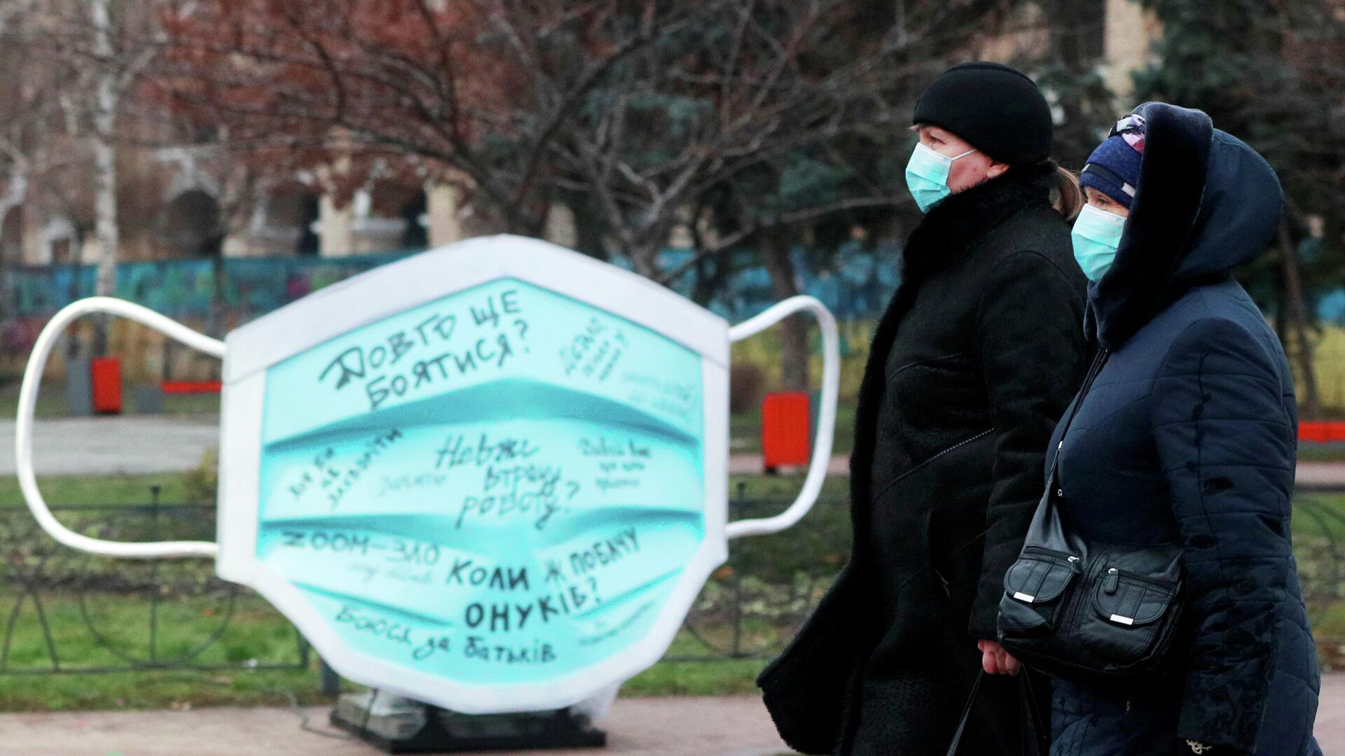 Женщины проходят мимо инсталляции в виде защитной маски на улице в Киеве - РИА Новости, 1920, 15.01.2021