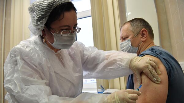 Медработник во время вакцинации от коронавируса COVID-19 вакциной Спутник V 