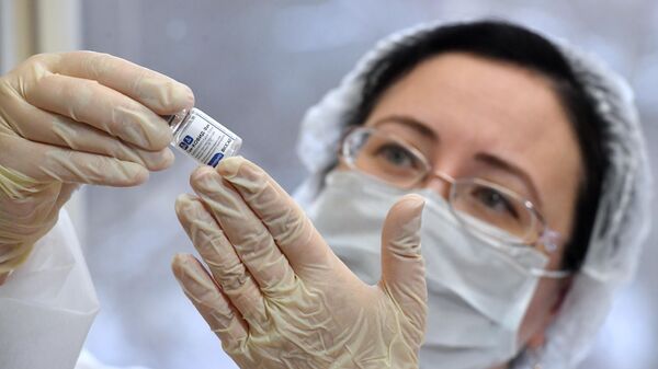 Медработник с вакциной Спутник V от коронавируса COVID-19