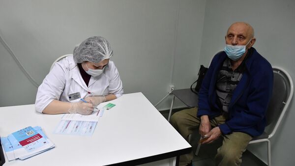 Медработник заполняет сертификат о вакцинации от новой коронавирусной инфекции COVID-19 для пожилого пациента после вакцинации вакциной Спутник V