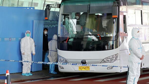 Группа экспертов ВОЗ садятся в автобус перед отъездом из международного аэропорта Ухань