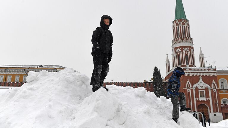 Дети играют на снежной горке на Красной площади в Москве