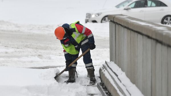Сотрудник коммунальной службы чистит от снега улицу