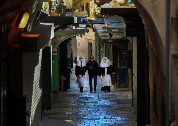 Монахини и мужчина в защитных масках на Виа Долороза в Старом городе Иерусалима