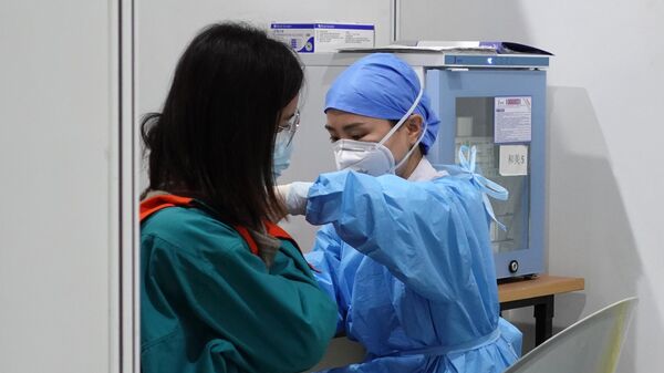 Медицинский работник во время вакцинации пациента от коронавируса в Пекине