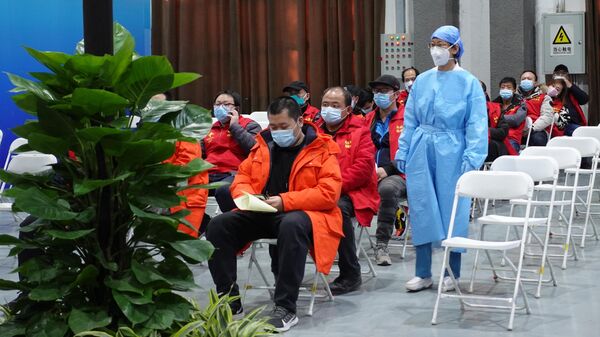 Медицинский работник и посетители в центре вакцинации от коронавируса в Пекине