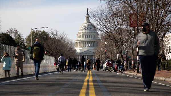Люди прогуливаются по одной из улиц неподалеку от здания Капитолия в Вашингтоне
