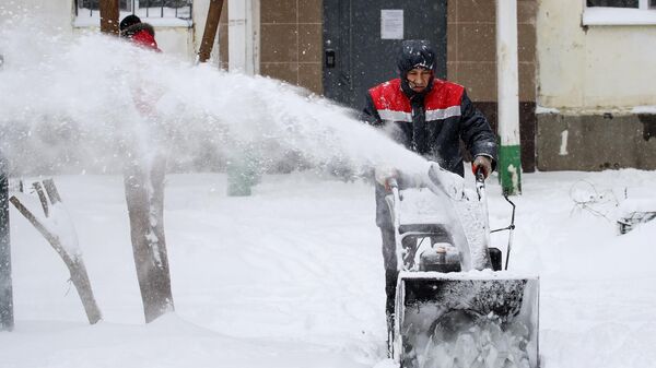 Сотрудник коммунальной службы проводит чистку снега в Краснодаре