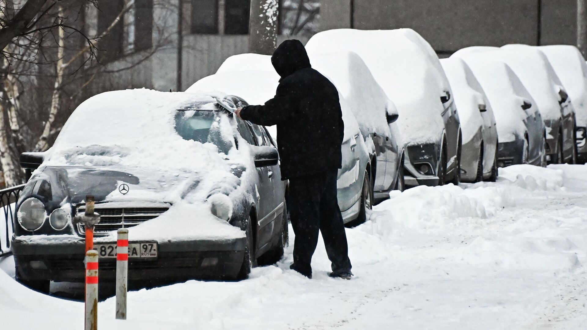 Мужчина очищает автомобиль от снега в Москве - РИА Новости, 1920, 18.01.2021