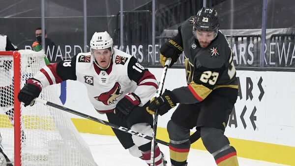 LAS VEGAS, NEVADA - JANUARY 18: Alec Martinez #23 of the Vegas Golden Knights clears the puck under pressure from Christian Dvorak #18 of the Arizona Coyotes in the third period of their game at T-Mobile Arena on January 18, 2021 in Las Vegas, Nevada. The Golden Knights defeated the Coyotes 4-2.   Ethan Miller/Getty Images/AFP