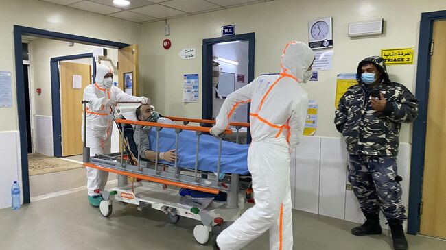 Медицинские работники транспортируют пациента в отделении для больных коронавирусом в больнице Дейр Аль-Амаль в провинции Бекаа-Хермель в Ливане