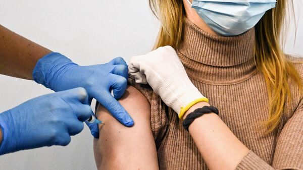 Девушке делают прививку от коронавируса в Геликон-опере в Москве