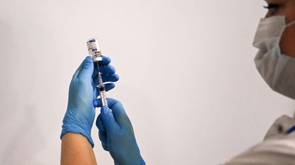 Медицинский сотрудник держит в руках вакцину Спутник-V в пункте вакцинации, открывшемся в театре Геликон-Опера, в Москве