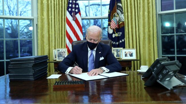 Президент США Джо Байден подписывает документы в в Овальном кабинете Белого дома в Вашингтоне после церемонии инаугурации