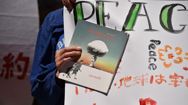 Участник митинга против ядерного оружия держит книгу с изображением ядерного взрыва