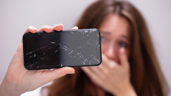 Девушка держит смартфон с разбитым экраном