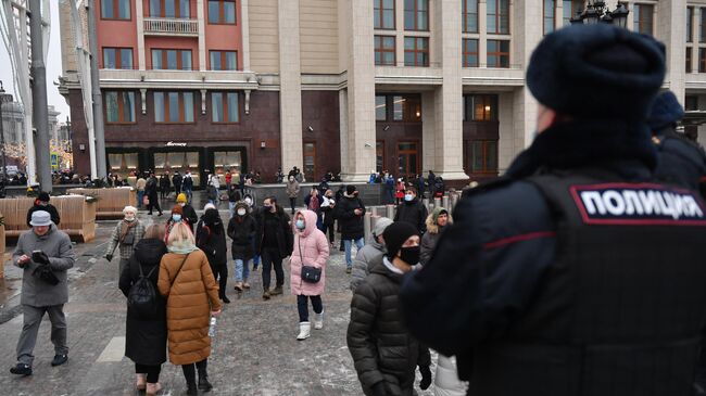 Сотрудник полиции и люди на Манежной площади в Москве во время несанкционированной акции сторонников Алексея Навального