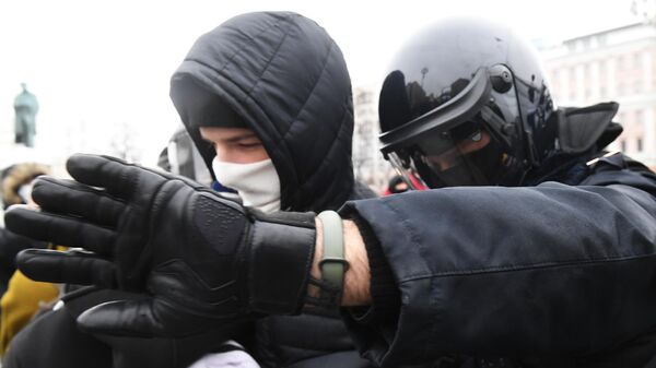 Сотрудник правоохранительных органов задерживает участника несанкционированной акции сторонников Алексея Навального в Москве