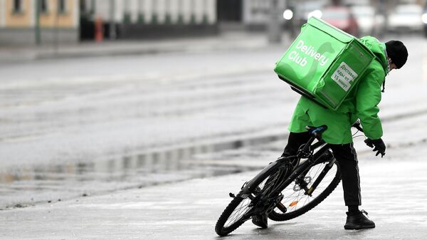 Курьер службы доставки Delivery Club едет на велосипеде на одной из улиц в Москве.
