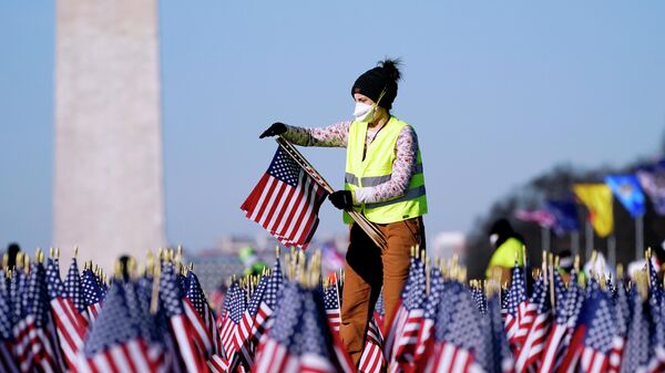 Женщина убирает флаги с Национальной аллеи после инаугурации президента США Джо Байдена в Вашингтоне