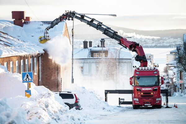 Уборка снега на крыше в центре Эрншёльдсвика, Швеция