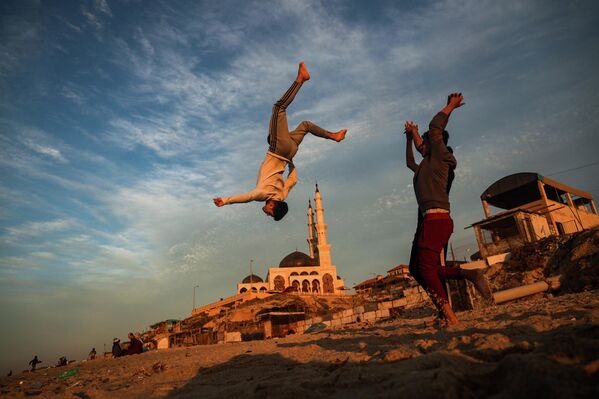 Палестинские дети занимаются паркуром на пляже в городе Газа