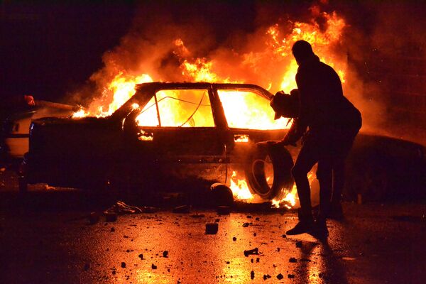 Горящий автомобиль во время антиправительственных протестов в ливанском Триполи