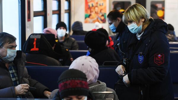 Контролеры в защитных масках проверяют наличие билетов у пассажиров в электропоезде в Новосибирске
