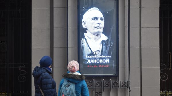 Люди у портрета Василия Ланового на здании Государственного академического театра имени Евгения Вахтангова в Москве
