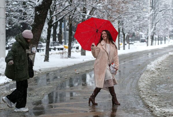 Девушки переходят дорогу по мокрому снегу в Краснодаре