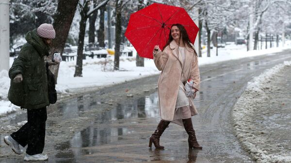 Девушки переходят дорогу по мокрому снегу в Краснодаре