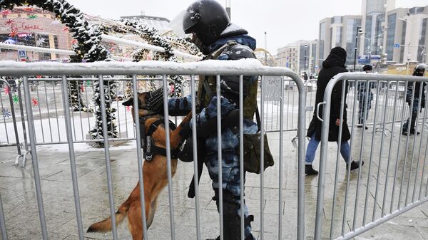 Сотрудник правоохранительных органов с собакой перед началом несанкционированной акции