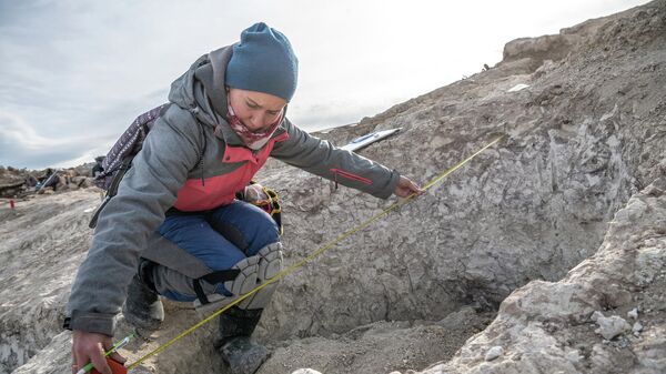 Участница экспедиции измеряет размер могильной ямы во время исследования грунтового могильника Киль-Дере близ Севастополя