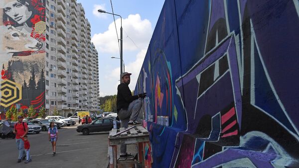 Уличный художник рисует граффити