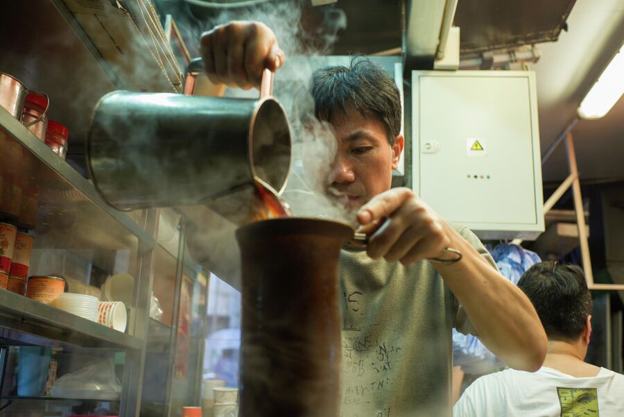 Мастер готовит чай с молоком в чайном магазине в Гонконге