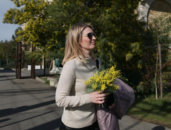 Девушка с  цветами мимозы на одной из улиц в Сочи