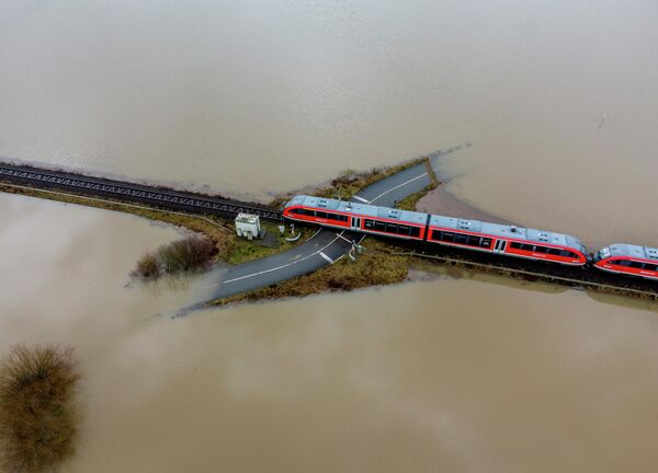 Поезд проезжает железнодорожный переезд во время наводнения в Ниддерау близ Франкфурта, Германия