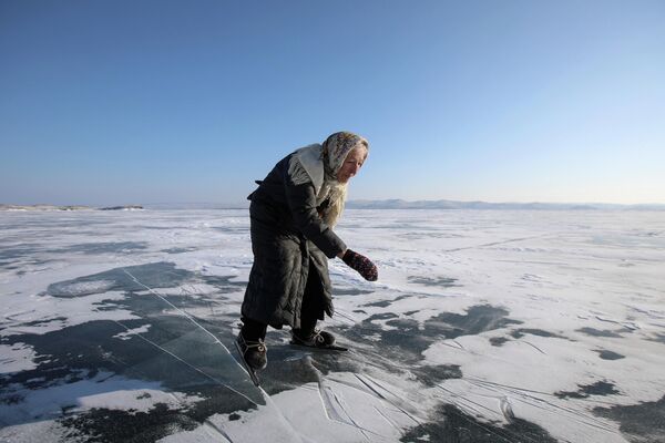 Бабушка катается на коньках по покрытому льдом озеру Байкал в Иркутской области, Россия