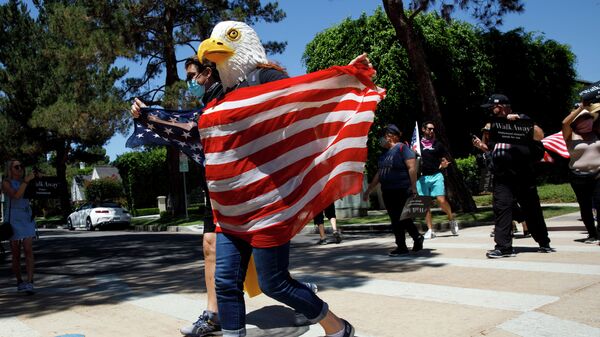 Демонстрант в маске орла с флагом США в Калифорнии